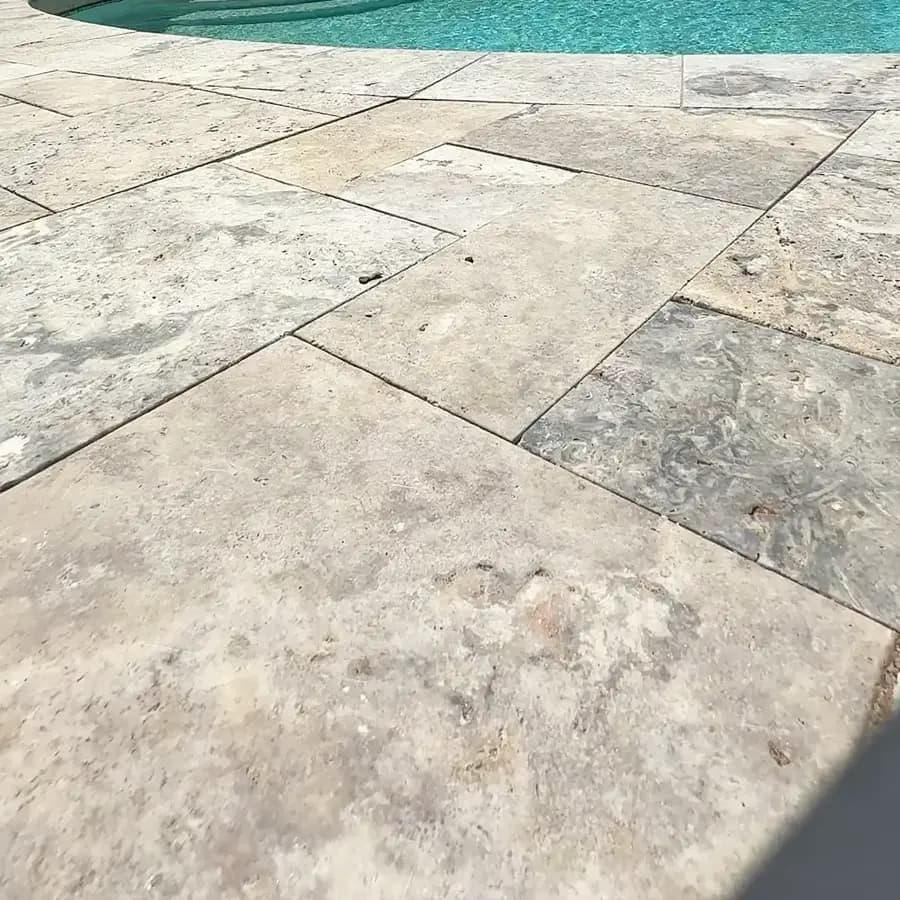Close-up of French-pattern silver travertine paving on a Tucson pool deck