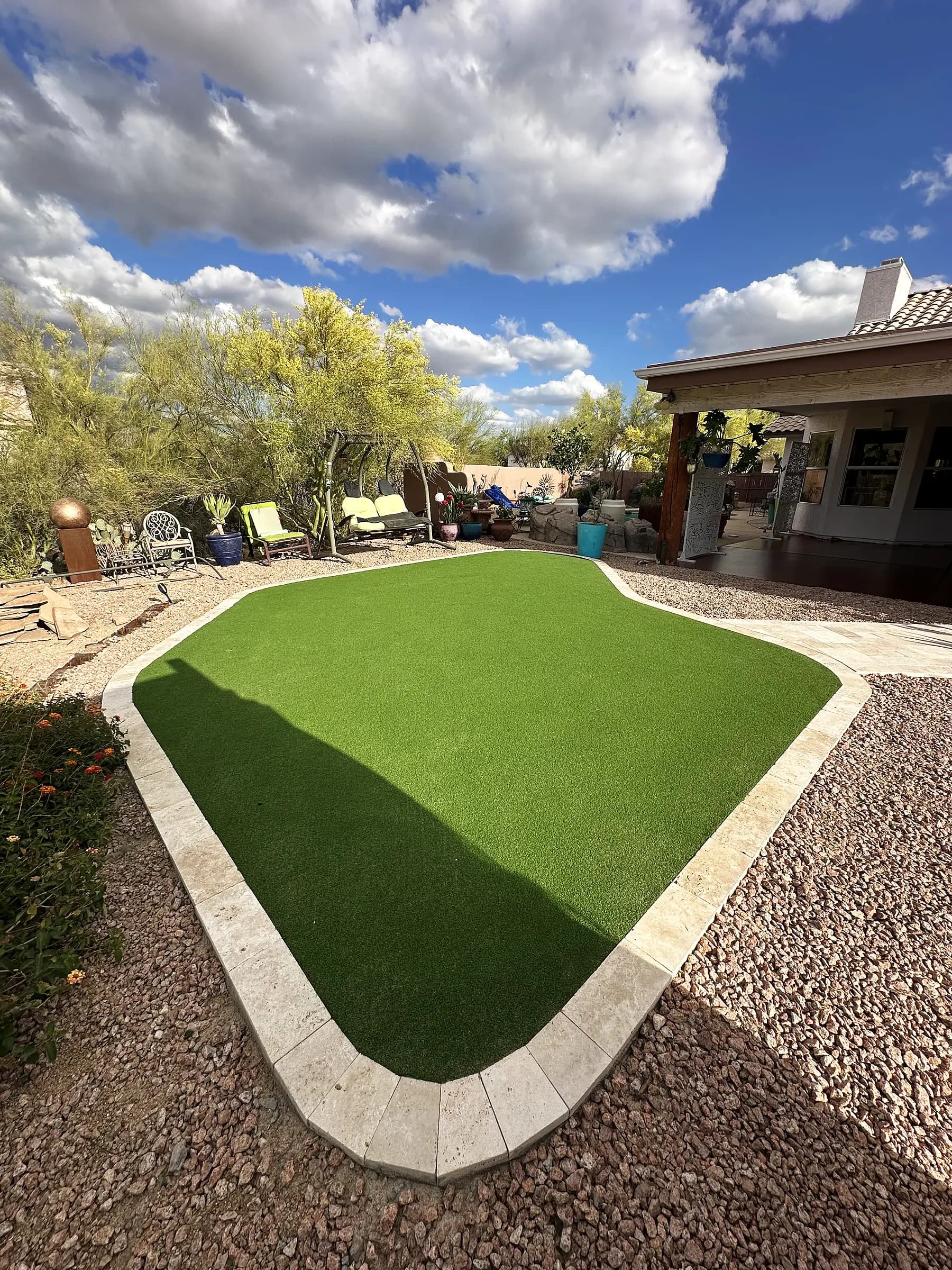 Artificial turf lawn edged in travertine border stone against desert landscaping